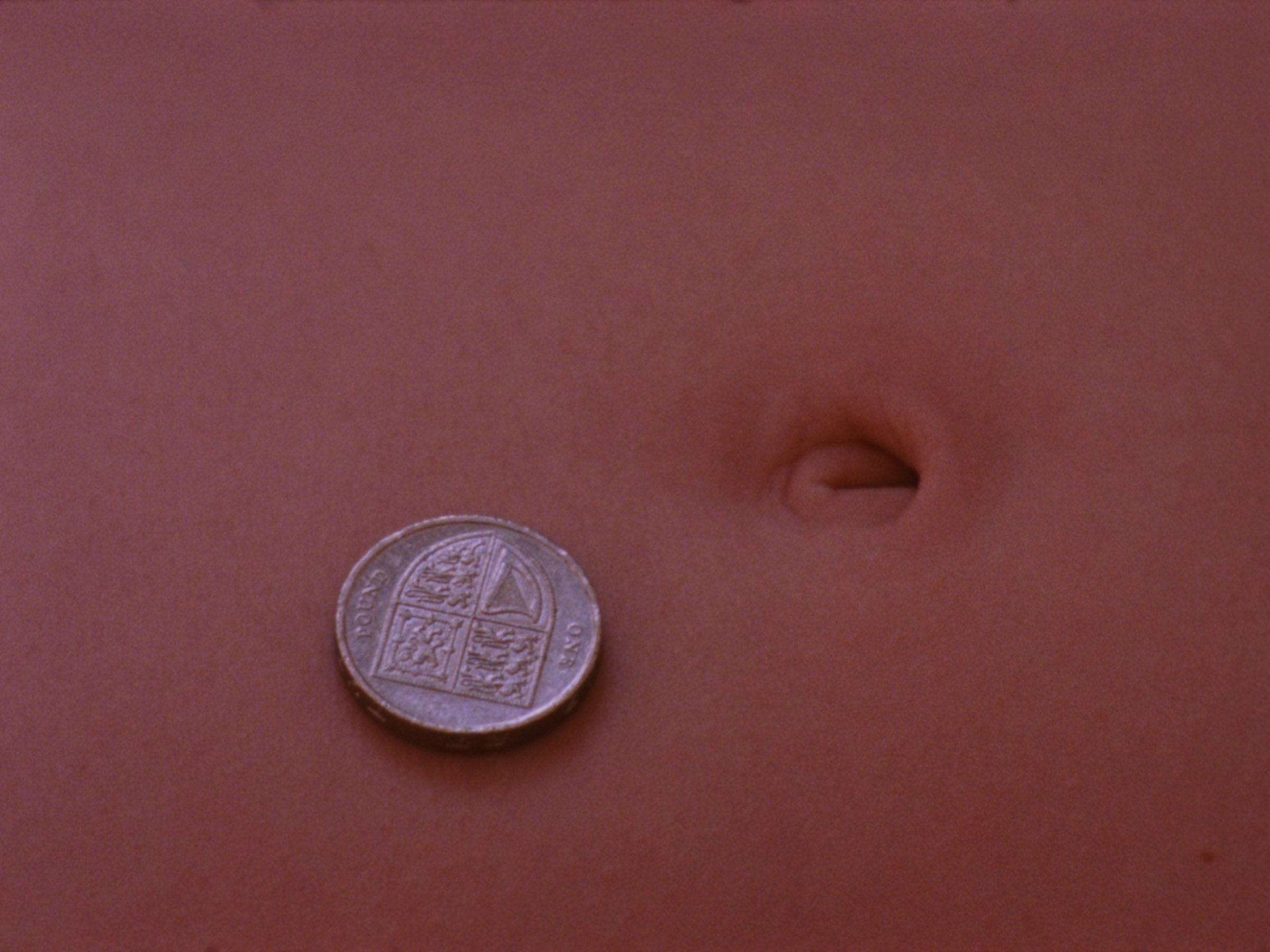 16 mm film still: a one pound coin and and bellybutton