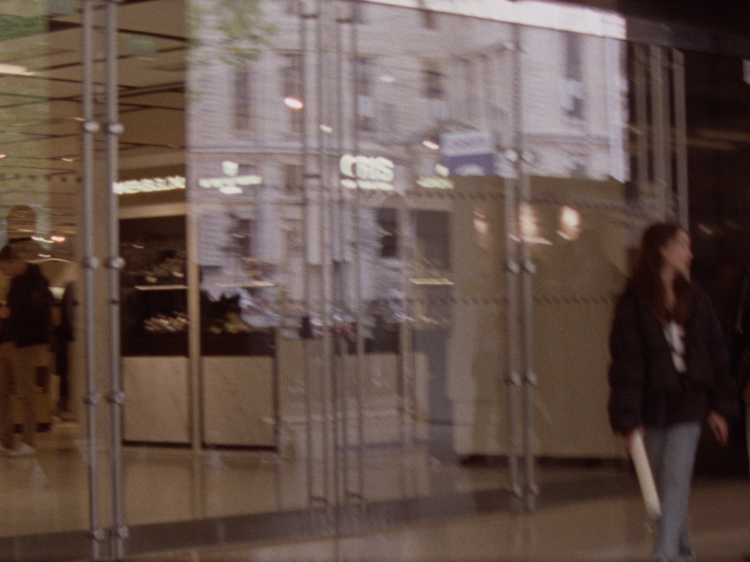 16 mm film still: a blurry image of the doors of the Galeries Lafayette