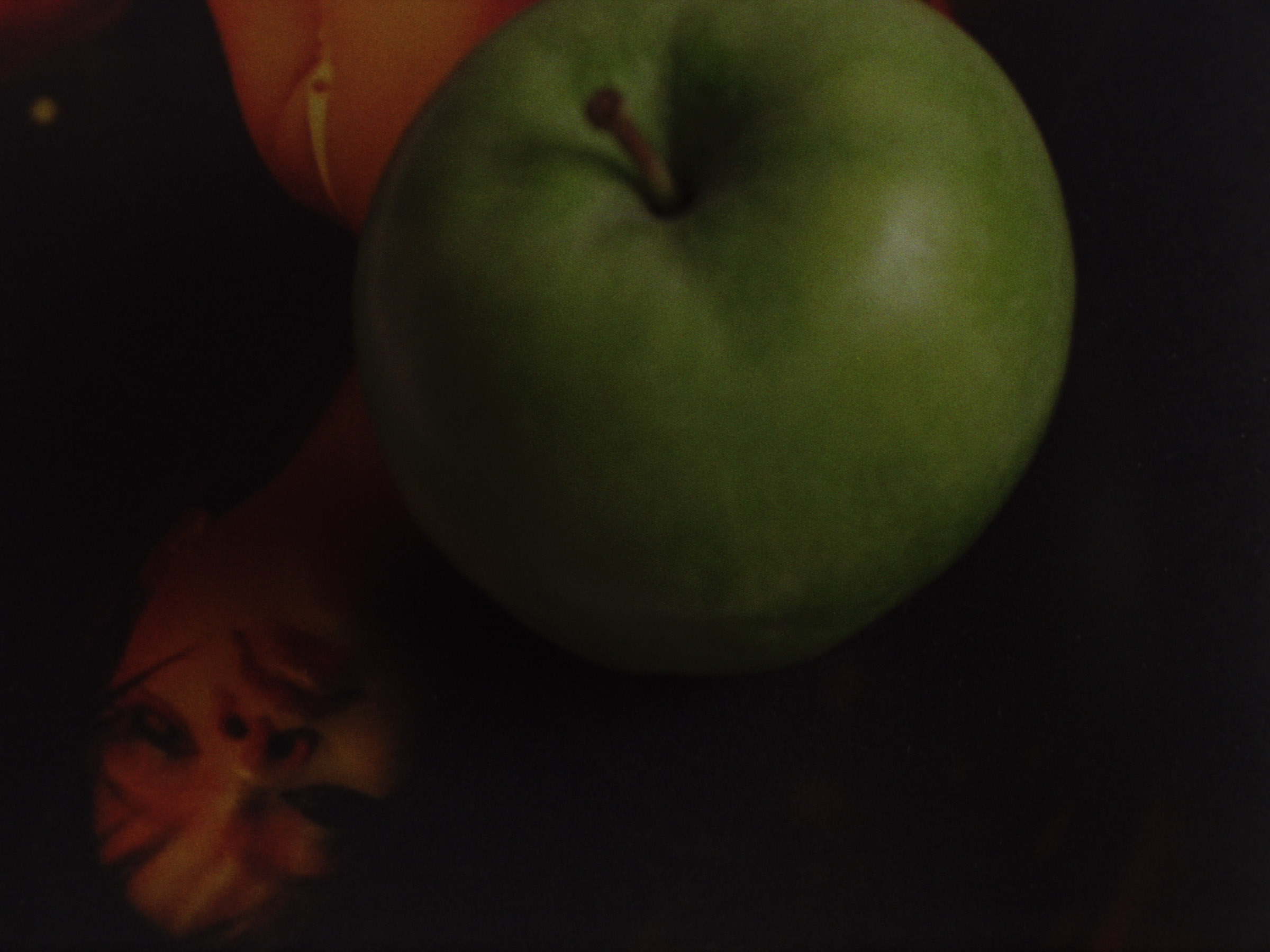 16 mm film still: a green apple lying on a picture of Rihanna
