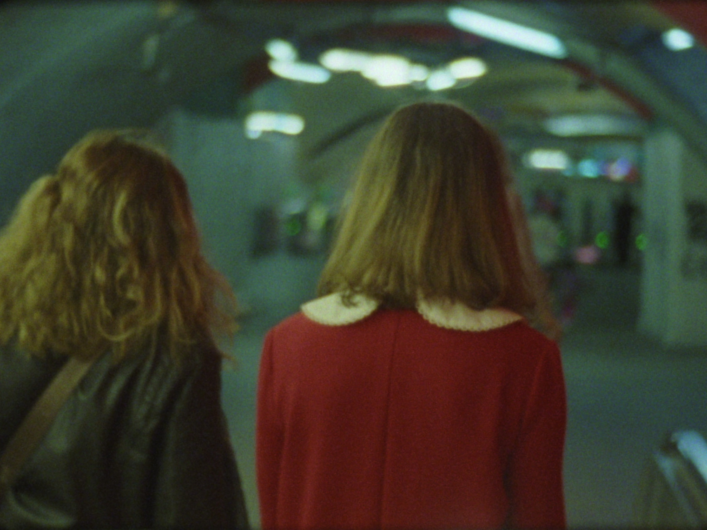 16 mm film still: a woman dressed up as Veruca Salt walking in a red hallway in the Paris metro